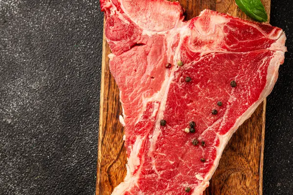 Çiğ biftek T-bone taze et prim biftek aperatif taze lezzetli gurme yemek arka planı masa rustik gıda üst görünüm fotokopi alanı
