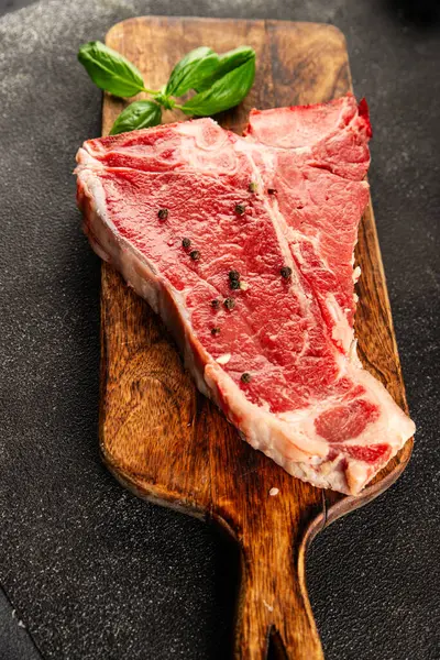 Çiğ biftek T-bone taze et prim biftek aperatif taze lezzetli gurme yemek arka planı masa rustik gıda üst görünüm fotokopi alanı