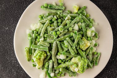 Donmuş yeşil sebzeler bezelye, brokoli, çalı fasulyesi, kohlrabi lahanası lezzetli çerez masadaki lezzetli gurme yemek arka planı rustik yemekler fotokopi alanı keto ve paleo diyeti vejetaryen ve vejetaryen yemekleri.