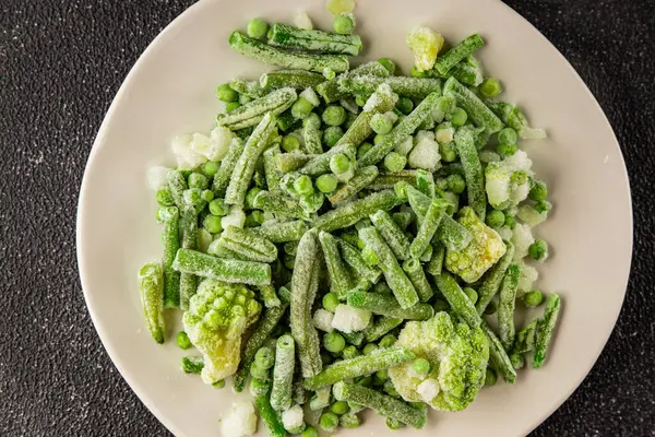 Donmuş yeşil sebzeler bezelye, brokoli, çalı fasulyesi, kohlrabi lahanası lezzetli çerez masadaki lezzetli gurme yemek arka planı rustik yemekler fotokopi alanı keto ve paleo diyeti vejetaryen ve vejetaryen yemekleri.
