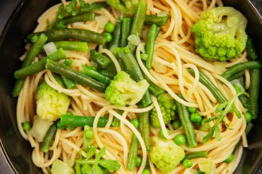 Spagetti sebzesi, bezelye, brokoli, çalı fasulyesi, kohlrabi vejetaryen makarna lezzetli makarna masanın üzerinde taze lezzetli gurme yemek.