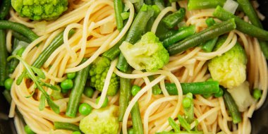 Spagetti sebzesi, bezelye, brokoli, çalı fasulyesi, kohlrabi vejetaryen makarna lezzetli makarna masanın üzerinde taze lezzetli gurme yemek.