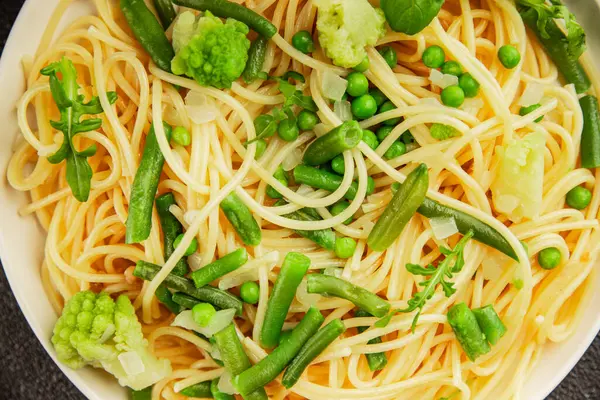 Spagetti sebzesi, bezelye, brokoli, çalı fasulyesi, kohlrabi vejetaryen makarna lezzetli makarna masanın üzerinde taze lezzetli gurme yemek.