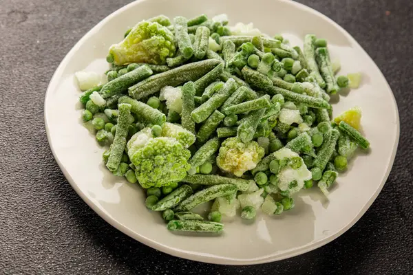 Donmuş yeşil sebzeler bezelye, brokoli, çalı fasulyesi, kohlrabi lahanası lezzetli çerez masadaki lezzetli gurme yemek arka planı rustik yemekler fotokopi alanı keto ve paleo diyeti vejetaryen ve vejetaryen yemekleri.