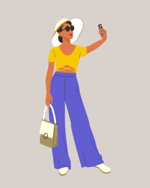 Genç bir kadın selfie çekiyor. Yaz modası görünüşü, geniş kenarlı şapka, gözlük, pantolon ve tişört. Vektör düz biçimi