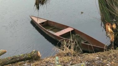 A lonely boat stands anchored on the water, its wood weathered and worn by the elements. Creating a serene yet melancholy atmosphere.