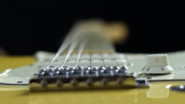 Macro shot of 6 string electric guitar. reveals the intricate details of the vintage yellow guitar, with a focus on the strings highlighting their smooth surface and qualities.