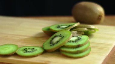 Taze yeşil kivi dilimleri güzel bir şekilde sade ahşap bir tahta üzerinde dizilir ve harika bir sunum oluşturur.