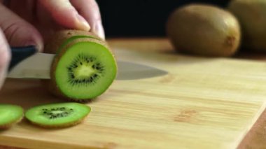 Taze yeşil bir kivi, eşsiz dokusunu ve detaylarını vurgulamak için kırsal bir ahşap tahta üzerinde dilimleniyor.