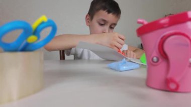 Genç bir çocuk, oyun için canlı materyaller ve araçlar kullanan çeşitli yaratıcı faaliyetlere son derece odaklanmıştır.