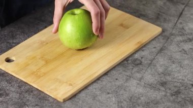 Kırsal bir ahşap kesme tahtasının üzerinde duran canlı yeşil bir elma çeşitli yemek ve sağlıklı tarifler için mükemmeldir.