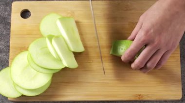 Yetenekli bir el, çıtır yeşil bir elmayı ustalıkla dilimler. Mutfakta taze ve sağlıklı malzemeler sergiler.