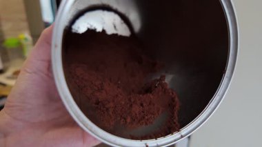 Parlak, paslanmaz çelik bir konteynırın içinde özenle depolanmış zengin kahve tozuna ayrıntılı bir bakış.