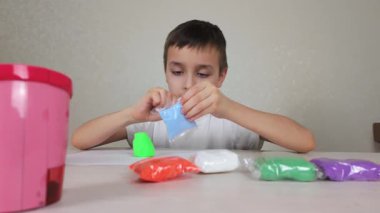 Genç bir çocuk masandaki çeşitli renkli el sanatları malzemelerini kullanarak yaratıcılığını keşfediyor.