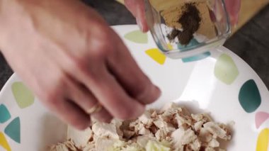 Yetenekli bir el, lezzetli bir salata için bir kase doğranmış tavuk ve taze sebzeye baharat ekler.
