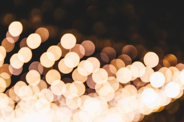 Odaklanamayan altın bokeh xmas ışıkları karanlık ışıkta. Soyut tatil ışıkları arka planı. Noel kutlaması duvar kâğıdı ya da kartpostal. Yeni yıl fotokopi alanı kutlaması kavramı. 