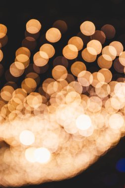 Duvar kâğıdı için odağını kaybetmiş bir Noel ışığı dikey resmi. Yeni yıl arifesini coşkulu bir şenlikle kutluyoruz. Parıldayan klasik ışıklar arka planında. Kart arkaplanı olarak açık altın ve siyah.