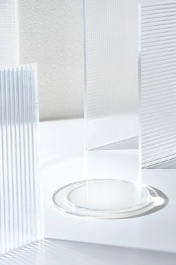 Şeffaflık kaidesi ürünü modern şeffaflık camının parlak beyaz arka planını günışığı ile sergiliyor.