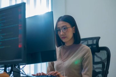 Ofiste bilgisayar monitörünün önünde duran yazılım verisi ile Asyalı komut mühendisi kodlama uygulaması