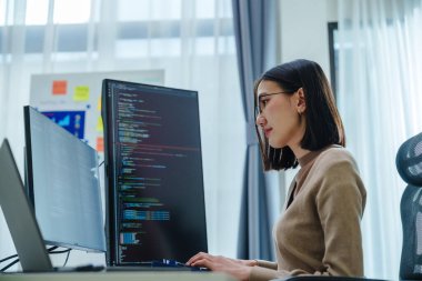 Ofiste bilgisayar monitörü önünde oturan Asyalı mühendis yazılım verileri ile kodlama uygulaması geliştirdi