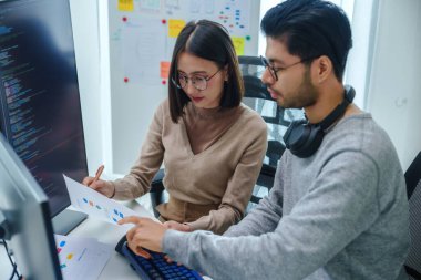 Asyalı ve Hintli Geliştirici ekibi ofisteki yazılım bilgisayarı ile geri bildirim analizi kodlama verilerini tartıştı