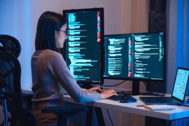 Asyalı kadın yazılım geliştirme modern ofiste bilgisayar ekranı ve akış şeması üzerinde çalışıyor