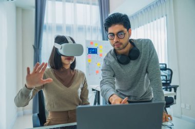 Sanal gerçeklik kulaklığı takan Asyalı yazılım geliştiricisi bir meslektaşıyla birlikte bir sanal gerçeklik projesinde çalışıyor.