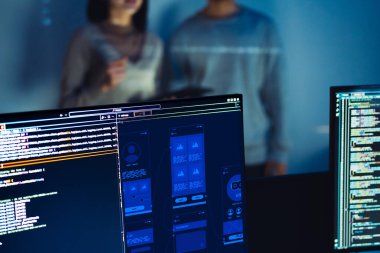 UX tasarımcısı bir tablet üzerinde çalışırken, meslektaşı ofisteki arka planda başvuruyu test ediyor.