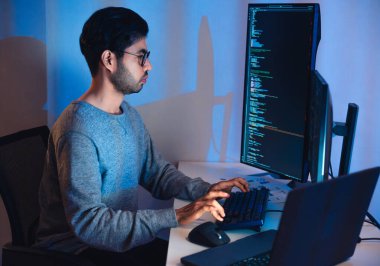 Hintli yazılım geliştirme modern ofiste bilgisayar ekranı ve akış şeması üzerinde çalışıyor