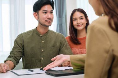 Çift müvekkil toplantısı sırasında tablet üzerinde dosya ve veri sunan Asyalı mali danışman. Finansal planlama ve karar verme