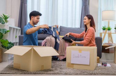 Bir grup arkadaş, kıyafetlerini bir bağış kutusuna yerleştiriyor ve paketliyor. Toplum desteği ve hayır kurumlarına bağış yapıyor.