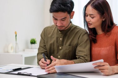 Çift müvekkil toplantısı sırasında tablet üzerinde dosya ve veri sunan Asyalı mali danışman. Finansal planlama ve karar verme