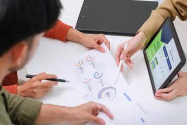 Çift müvekkil toplantısı sırasında tablet üzerinde dosya ve veri sunan Asyalı mali danışman. Finansal planlama ve karar verme