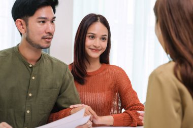 Çift müvekkil toplantısı sırasında tablet üzerinde dosya ve veri sunan Asyalı mali danışman. Finansal planlama ve karar verme