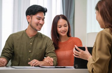 Çift müvekkil toplantısı sırasında tablet üzerinde dosya ve veri sunan Asyalı mali danışman. Finansal planlama ve karar verme