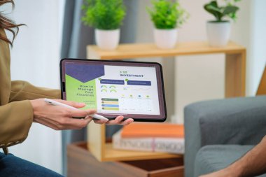 Çift müvekkil toplantısı sırasında tablet üzerinde dosya ve veri sunan Asyalı mali danışman. Finansal planlama ve karar verme