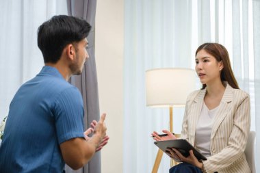 Asyalı bir adam sakin ve destekleyici bir ortamda profesyonel bir danışmanla birebir terapi seansına katıldı.