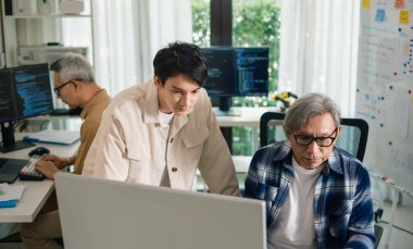 Bir acemi birliği kampı eğitimi sırasında akış çizelgelerini analiz eden bir grup Asyalı kıdemli yazılım geliştirici.