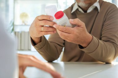 Tıbbi danışmanlık sırasında kıdemli hastaya ilacı açıklayan doktor.