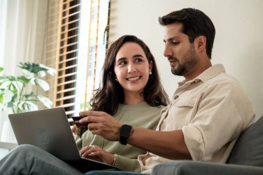 Mutlu çift, akıllı telefonlu kusursuz online alışveriş deneyimi için evde kredi kartı ve laptop kullanıyor.