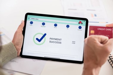 Çift e-ticaret uygulaması üzerinden online alışveriş yapmak için tablet ve kredi kartı kullanıyor, ödeme yapıyor ve tanıtım kodları ve indirimli modern platformlara göz atıyor