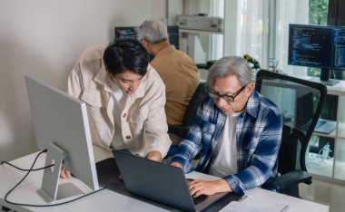 Bir acemi birliği kampı eğitimi sırasında akış çizelgelerini analiz eden bir grup Asyalı kıdemli yazılım geliştirici.