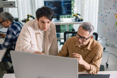 Bir acemi birliği kampı eğitimi sırasında akış çizelgelerini analiz eden bir grup Asyalı kıdemli yazılım geliştirici.