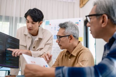 Bir acemi birliği kampı eğitimi sırasında akış çizelgelerini analiz eden bir grup Asyalı kıdemli yazılım geliştirici.