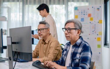 Bir acemi birliği kampı eğitimi sırasında akış çizelgelerini analiz eden bir grup Asyalı kıdemli yazılım geliştirici.