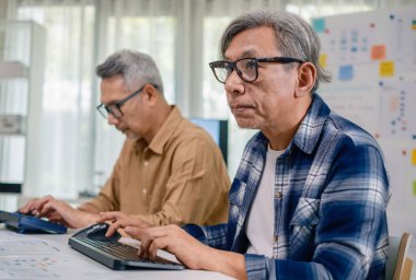 Bir acemi birliği kampı eğitimi sırasında akış çizelgelerini analiz eden bir grup Asyalı kıdemli yazılım geliştirici.