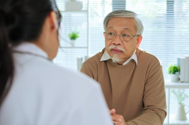 Klinikteki ya da hastanedeki yaşlı hastayla görüşürken Doktor Tıbbi Dosyayı İnceleme