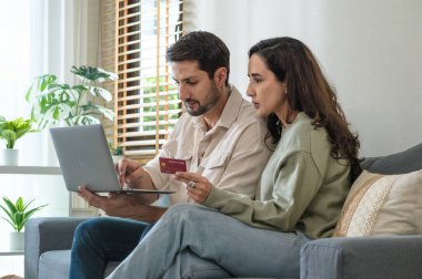 İspanyol çift elektronik ticaret uygulaması üzerinden online alışveriş yapmak için dizüstü bilgisayar ve kredi kartı kullanıyor, ödeme yapıyor ve promosyon kodları ve indirimlerle modern platformlara göz atıyor.