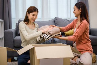 Bir grup arkadaş, kıyafetlerini bir bağış kutusuna yerleştiriyor ve paketliyor. Toplum desteği ve hayır kurumlarına bağış yapıyor.