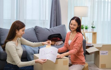 Bir grup arkadaş, kıyafetlerini bir bağış kutusuna yerleştiriyor ve paketliyor. Toplum desteği ve hayır kurumlarına bağış yapıyor.